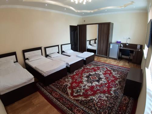 杜尚别City Hostel Dushanbe的一间卧室配有三张床、地毯和书桌