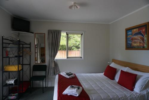 玛拉豪Abel Tasman Haven的一间卧室配有一张带红色枕头的床和一扇窗户