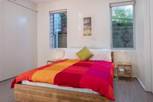 悉尼Bondi Lock-Down Retreat, The Cute Place To Put Up Your Feet的一间卧室配有一张色彩缤纷的床和两个窗户
