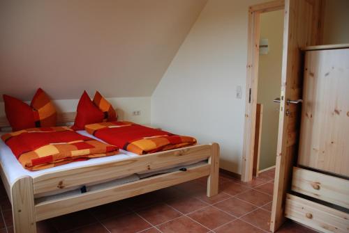 MechelsdorfOstseepension TonArt的一间卧室配有一张带红色和橙色枕头的木床。