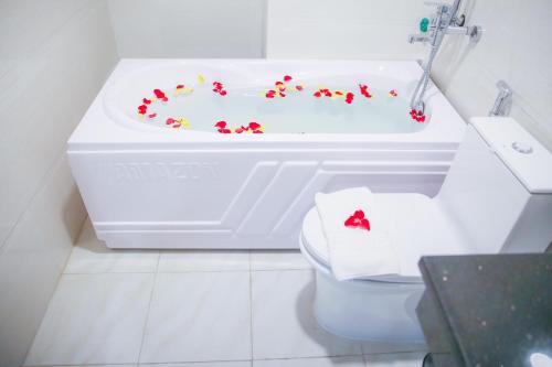 清化Long Anh Hotel的浴室设有卫生间和鲜花浴缸。