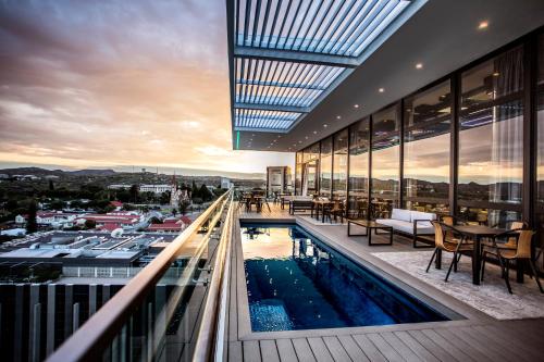 温特和克Avani Windhoek Hotel & Casino的一座带游泳池的建筑,位于阳台