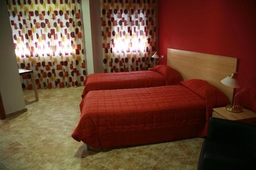 拉罗达HOSTAL EL POLIGONO的酒店客房设有两张床和红色的墙壁。