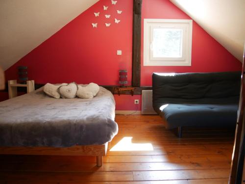 克松吕-隆日梅Chalet pour amoureux de la nature avec vue sur le lac de Retournemer的一间卧室设有红色的墙壁、一张床和一张沙发