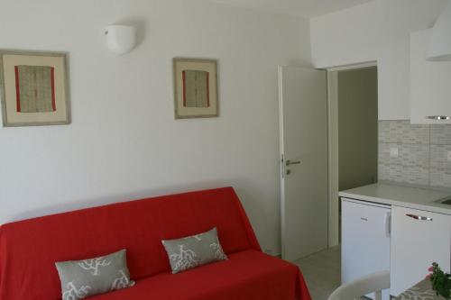 布尔纳Apartments Robert - 5m from the sea的一间带红色沙发的客厅和一间厨房