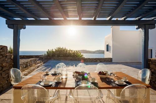 米克诺斯城AGL Luxury Villas的海景露台上的一张木桌和椅子