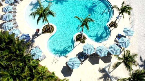 马拉松Isla Bella Beach Resort & Spa - Florida Keys的享有带蓝白遮阳伞的游泳池的顶部景致