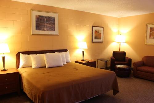 LakotaSunlac Inn Lakota的酒店客房,配有一张床、椅子和灯具