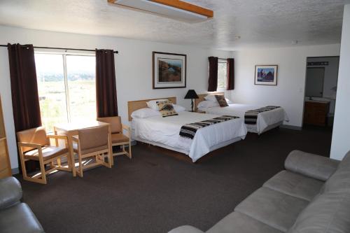 哈奇The Riverside Ranch Motel and RV Park Southern Utah的酒店客房带两张床、一张桌子和一张沙发