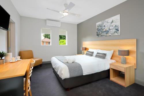 悉尼Kingsgrove Hotel的一间卧室配有一张床、一张书桌和一张书桌
