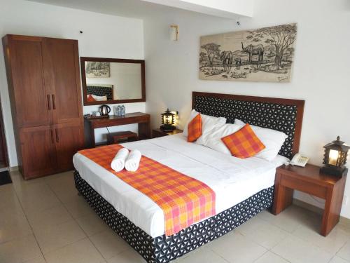 平纳瓦拉品纳兰达酒店的一间卧室配有带白色床单和橙色枕头的床。