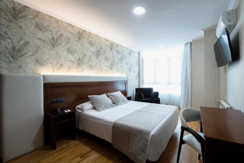 塞埃Hotel Oca Insua Costa da Morte的酒店客房设有一张大床和一张书桌。