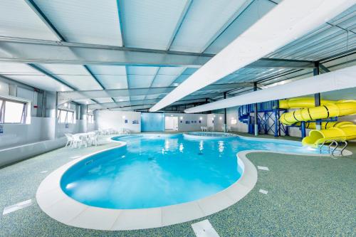 伯青顿Camping Pods, Birchington Vale Holiday Park的大楼内一个带滑梯的大型游泳池