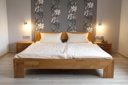 科堡Gästehaus Loehnert GmbH的一间卧室配有一张带白色床单的木床
