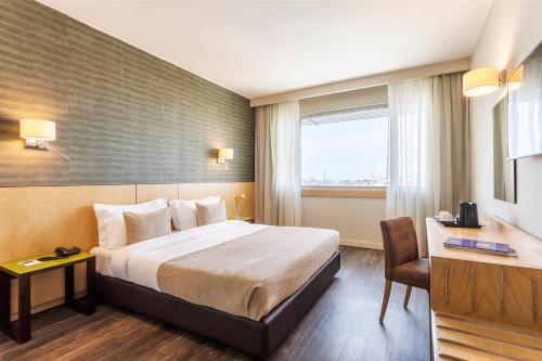 波尔图HF伊帕内玛波尔图的配有一张床、一张书桌和一扇窗户的酒店客房