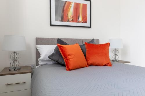 法恩伯勒Charlie Mews的一张带橙色和灰色枕头的床