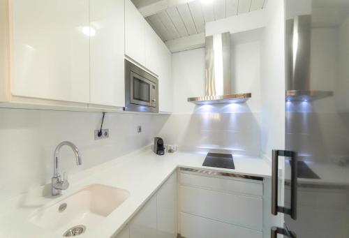 乌贝达Palacio del Agua Apartamentos的白色的厨房配有水槽和微波炉