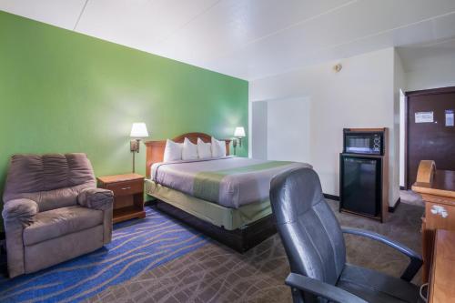 迪金森Badlands Inn & Suites的配有一张床和一把椅子的酒店客房