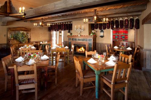 圣达菲Hotel Chimayo de Santa Fe的餐厅设有木桌、椅子和壁炉