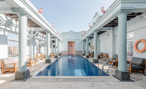 香港香港逸东酒店的一座带椅子的建筑屋顶上的室内游泳池