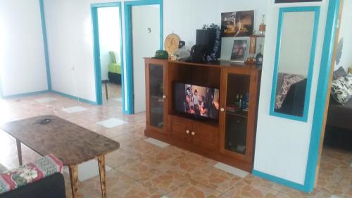 AmuriAitutaki Budget Accommodation的客厅配有电视和桌子