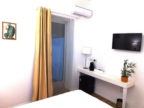 普雷西切B&B Suites Via del Mare的一间卧室配有一张床和一张书桌及电视