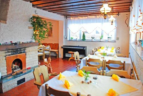 弗劳埃瑙Pension "Bayerwald"的一间带桌椅和壁炉的餐厅
