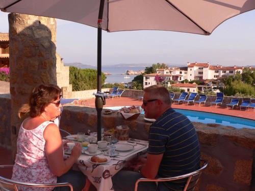 巴哈撒丁岛奥林匹亚酒店的坐在桌子下伞下的男人和女人