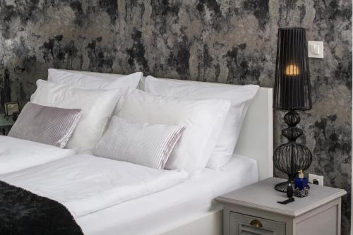 萨格勒布Note Luxury Apartments的一张白色的床,配有白色枕头和台灯