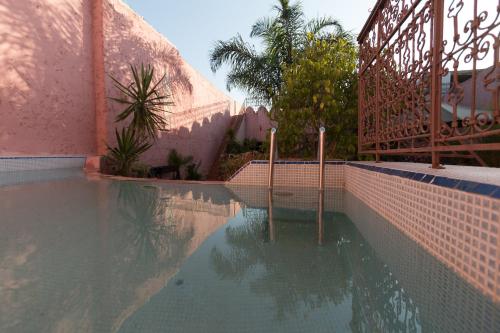 梅克内斯Riad El Ma的粉红色建筑旁边的游泳池