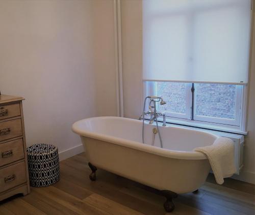 蒂尔堡NineT7的带窗户的浴室内的白色浴缸