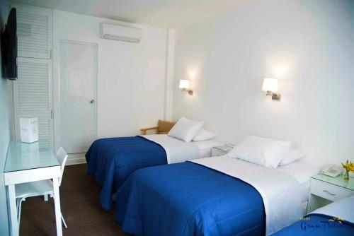皮乌拉Hotel Gran Palma Piura的酒店客房配有两张床和一张书桌