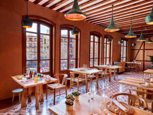 托莱多Hotel Boutique Adolfo的餐厅设有木桌、椅子和窗户。
