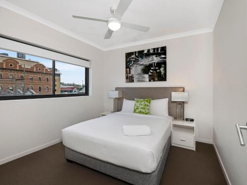 布里斯班阿特里奥公寓的白色的卧室设有床和窗户