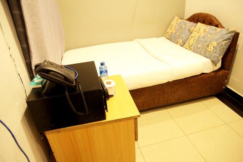 内罗毕Inks Hotel的一间设有一张床铺的房间,桌子上配有电话