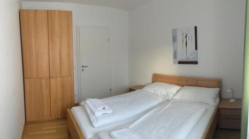 索内纳尔佩·纳斯费尔德Sonnenalpe Apartments Nassfeld的一间卧室配有一张床和一个木制橱柜