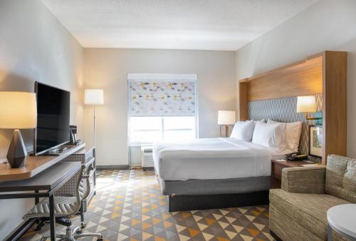 莫米Holiday Inn Toledo - Maumee I-80/90, an IHG Hotel的酒店客房配有一张床、一张书桌和一台电视。