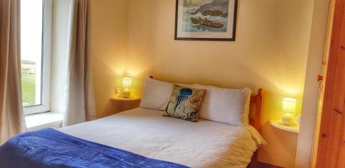 格伦贝赫Jacks' Coastguard Cottage Vacation home的一间卧室配有一张带两盏灯的床和一扇窗户。