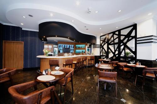 索罗卡巴Grand Hotel Royal Sorocaba by Atlantica的一间带木桌椅的餐厅和一间酒吧