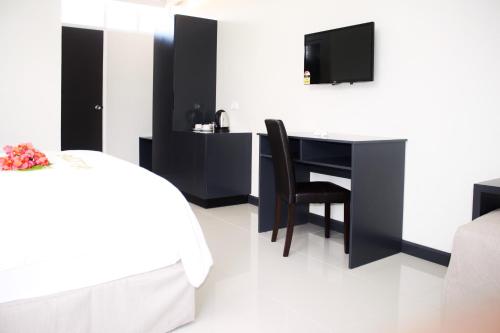 南迪绿洲酒店的一间卧室配有书桌、一张床和一台电视。