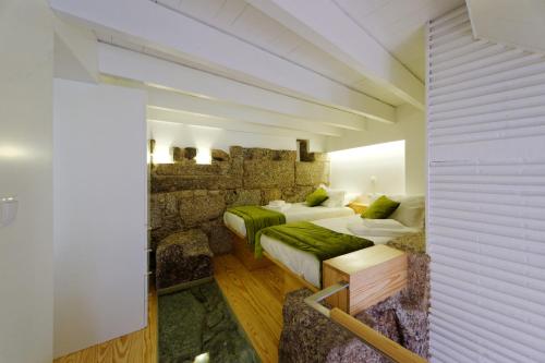 吉马良斯吉马良斯酒廊一室公寓的一间卧室设有两张床和石墙