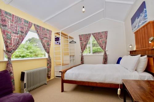 黑荒地Waragil Cottage - Original Settler's Home的一间卧室设有一张床和两个窗户。