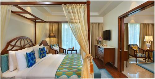帕纳吉Fortune Miramar, Goa - Member ITC's Hotel Group的一间带天蓬床的卧室和一间客厅