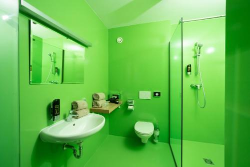 格拉茨Hotel Greenrooms的绿色浴室设有水槽和卫生间