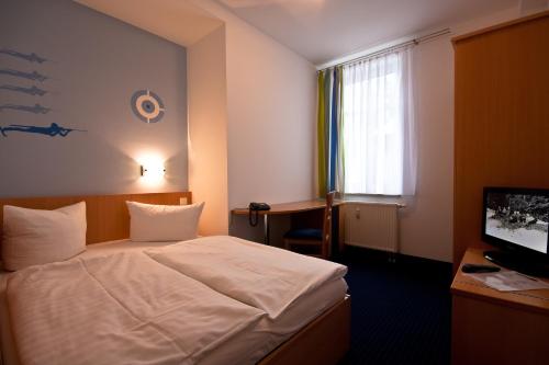 施泰纳赫史坦纳河户外健身酒店的一间卧室配有一张床、一张书桌和一台电视