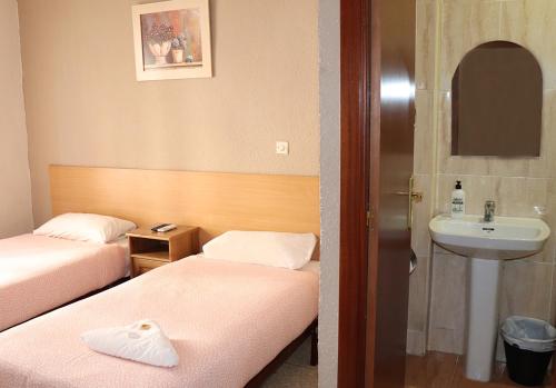 萨拉戈萨Pensión Fortea的酒店客房设有两张床和盥洗盆