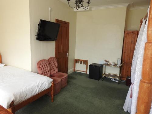 巴茅思Môr Wyn Guest House的一间卧室配有一张床、一台电视和一把椅子