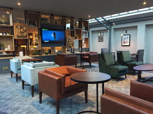 雷阿马斯顿经典英国马斯顿酒店的大堂配有沙发、桌子和平面电视。
