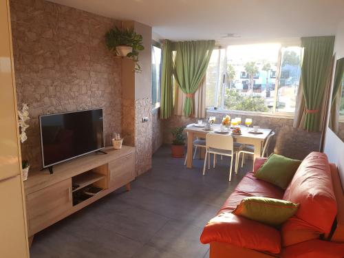 圣巴托洛梅Vista al mar playa del aguila!的带沙发、电视和桌子的客厅