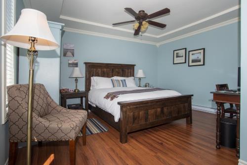 Bareneed湾畔住宿加早餐旅馆的一间卧室配有一张带吊扇和椅子的床